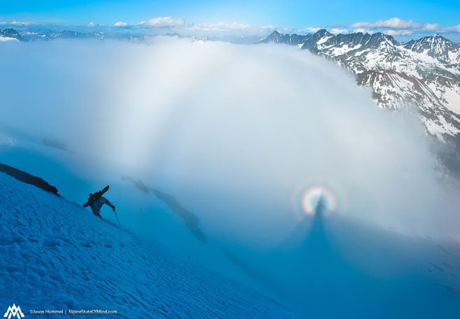 After a few days in the clouds on the American Alps Traverse, Kyle Miller climbs up the final slopes of Fortress Mountain while a Brocken Spectre blossoms in the clouds below.